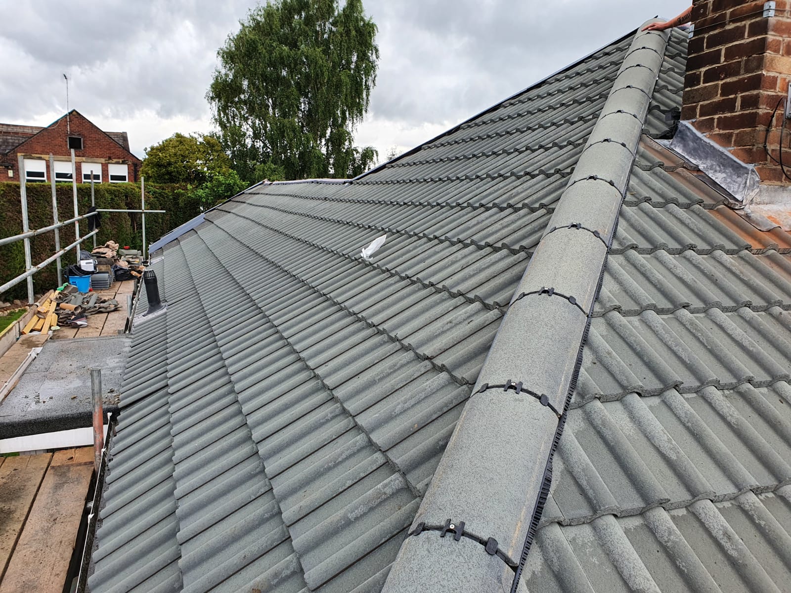 Newly laid grey interlocking tiled roof with bedded ridge