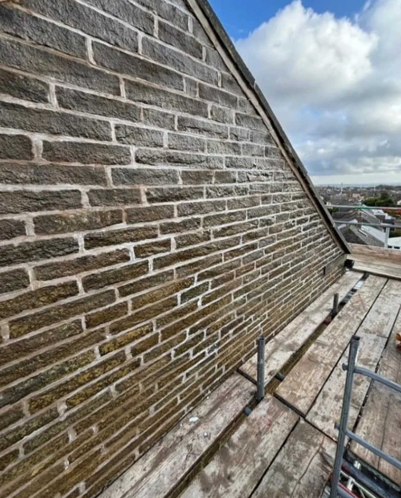 Repointed and sealed stone gable wall viewed from scaffold