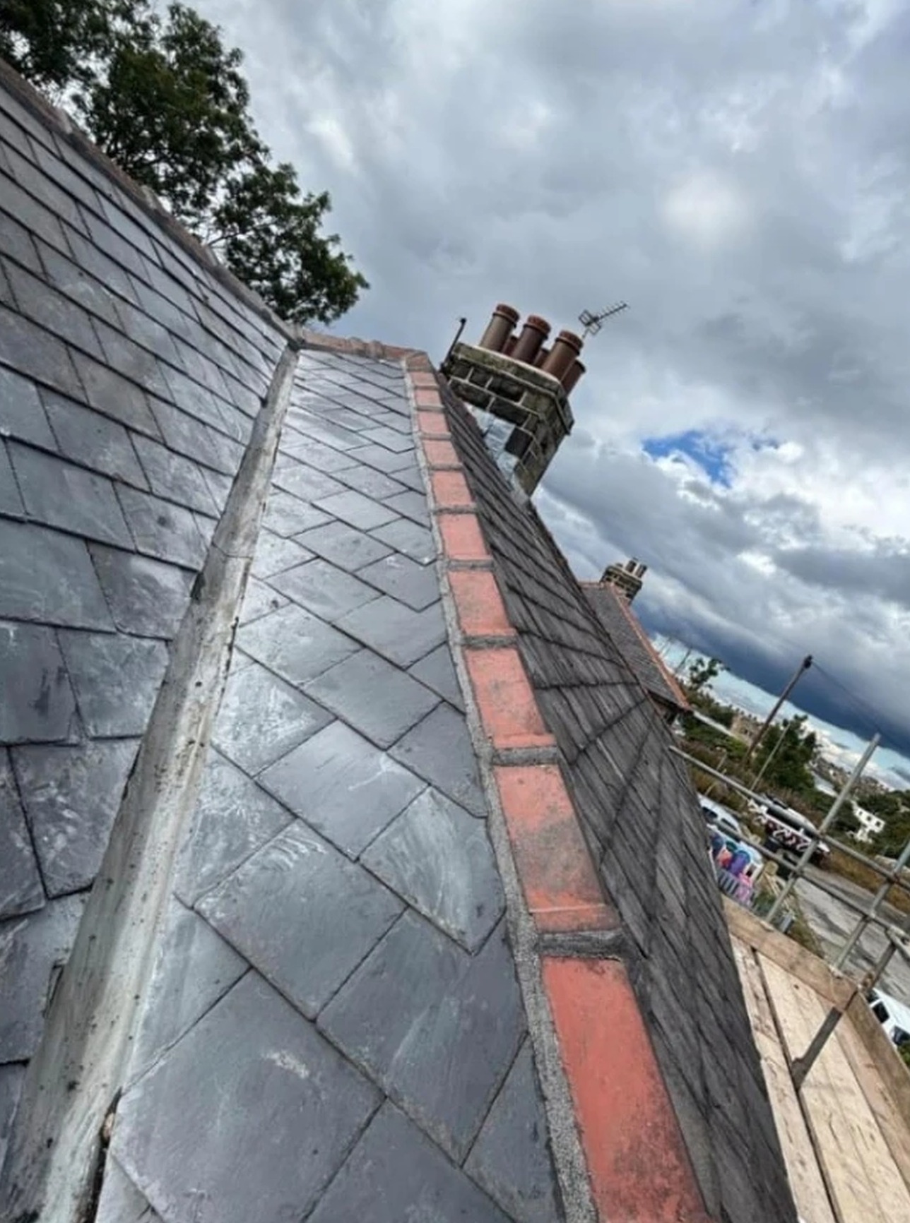 Newly formed valley between two slate roof slopes running up to a chimney stack