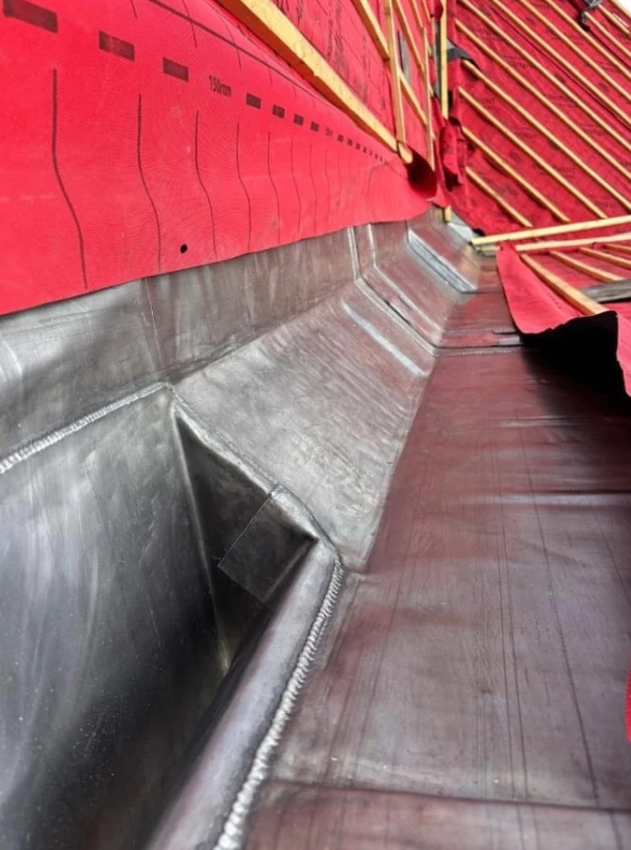 Welded lead valley gutter formed between two roof slopes over breathable underlay and battens